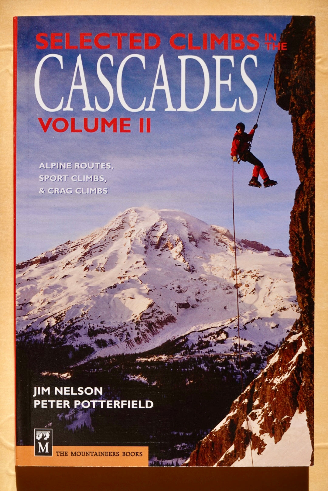 Book cover of 'Selected Climbs in the Cascades Volume II' with a climber rappelling on a mountain.